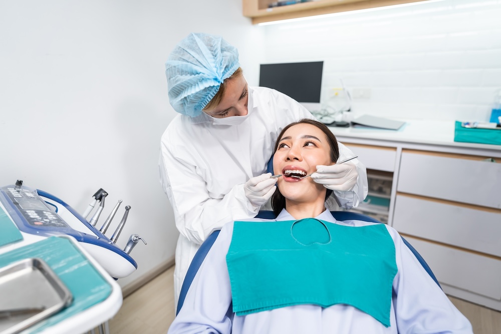A dentist wearing protective gear examining a patient's teeth in a modern dental clinic - Puyallup Dentist A dentist wearing protective gear examining a patient's teeth in a modern dental clinic - Puyallup Dentist